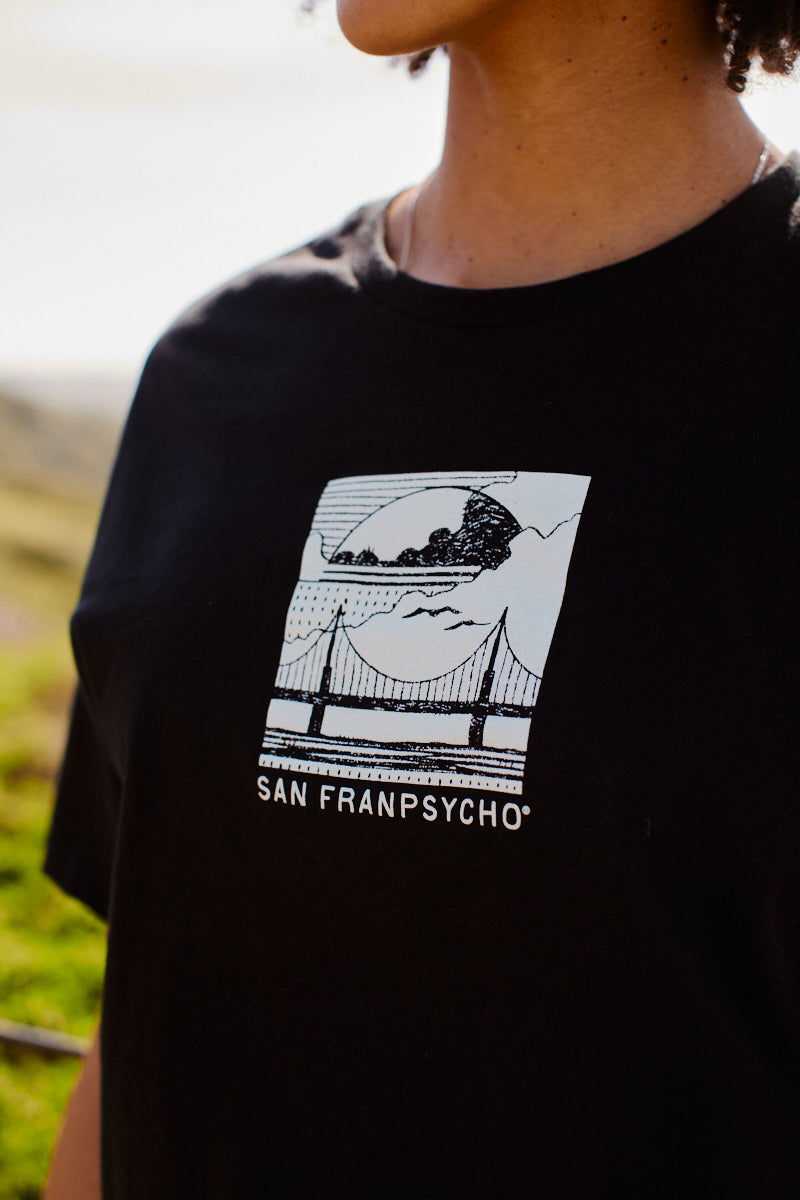 Model wears the Women's Elemental Cropped Tee in black, featuring a graphic bridge design and San Franpsycho text that captures the spirit of San Francisco.