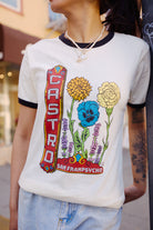 Wearing a Castro Pride Tee with colorful queer flowers outdoors—a vibrant nod to Pride design.
