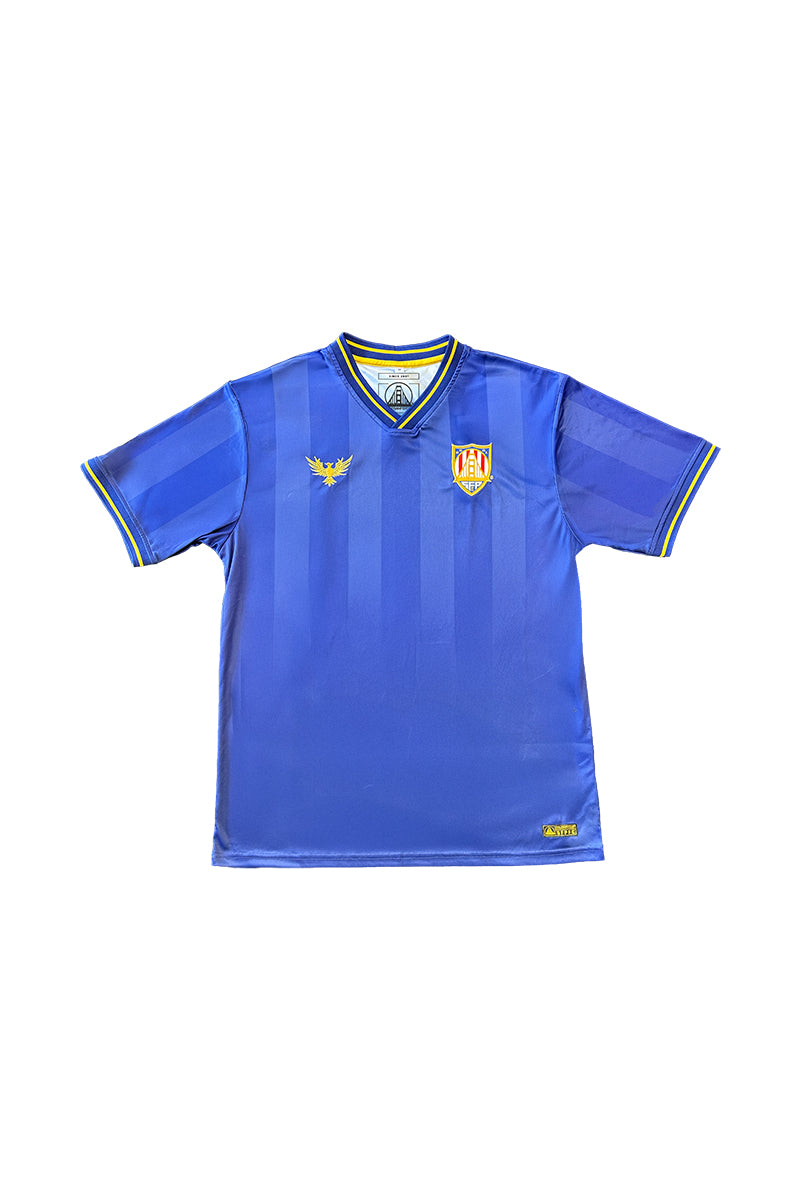 The WC x SFP Jersey - Blue is a short-sleeve soccer top with yellow details, dual crest logos on the chest, and a fan fit—perfect for US Men's National Team supporters and inspired by World Cup jerseys.