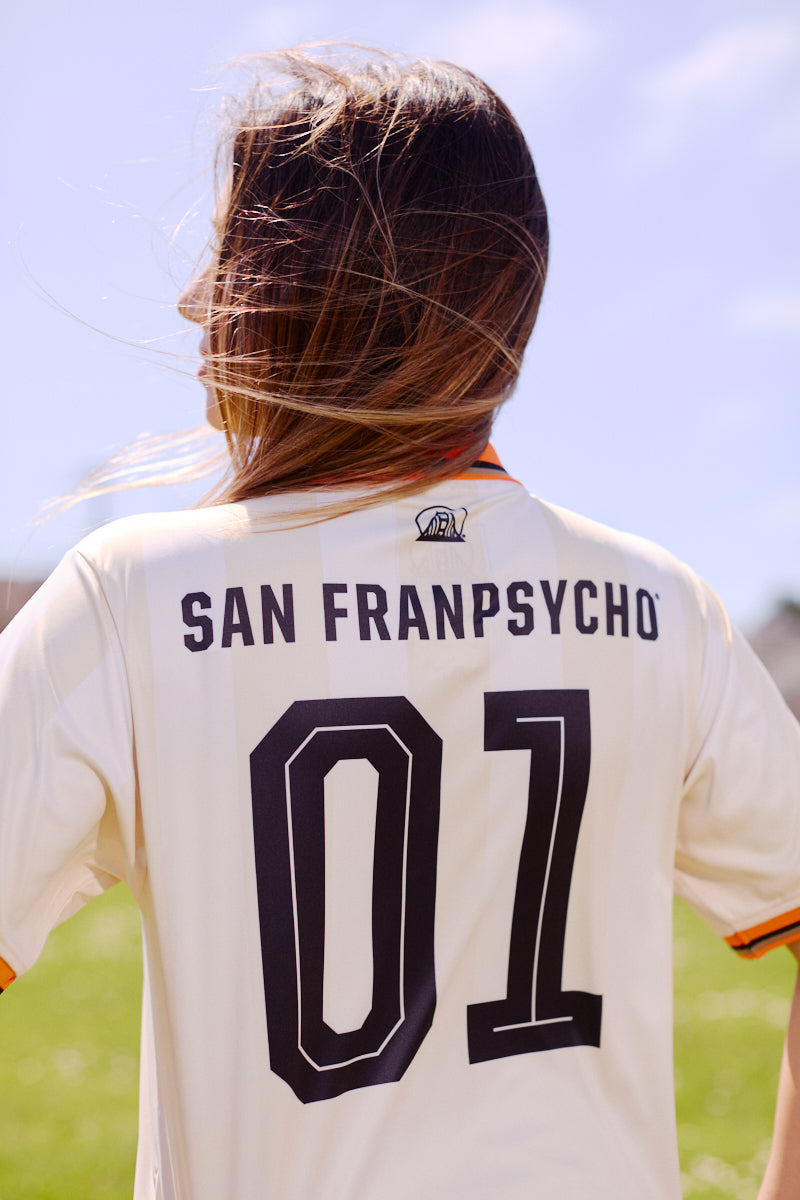 Person with long hair wearing the WC x SFP Jersey - Away, standing outdoors on a sunny day.