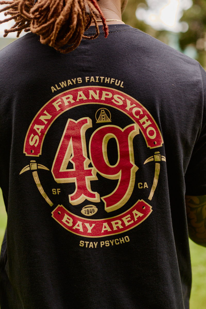 Wearing the Niners Faithful Tee, a black unisex t-shirt featuring San Franpsycho 49 Bay Area and graphic elements on the back—perfect for any fan representing San Francisco.