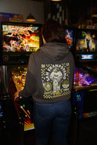 A person wears a dark grey Quarter Cent Crop Hoodie with a skull gumball machine graphic on the back.