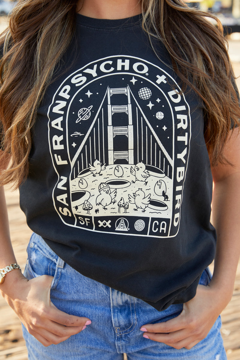 A woman wears the Moon Bridge Tee, a Dirtybird collaboration showcasing a San Francisco-inspired Golden Gate Bridge graphic.