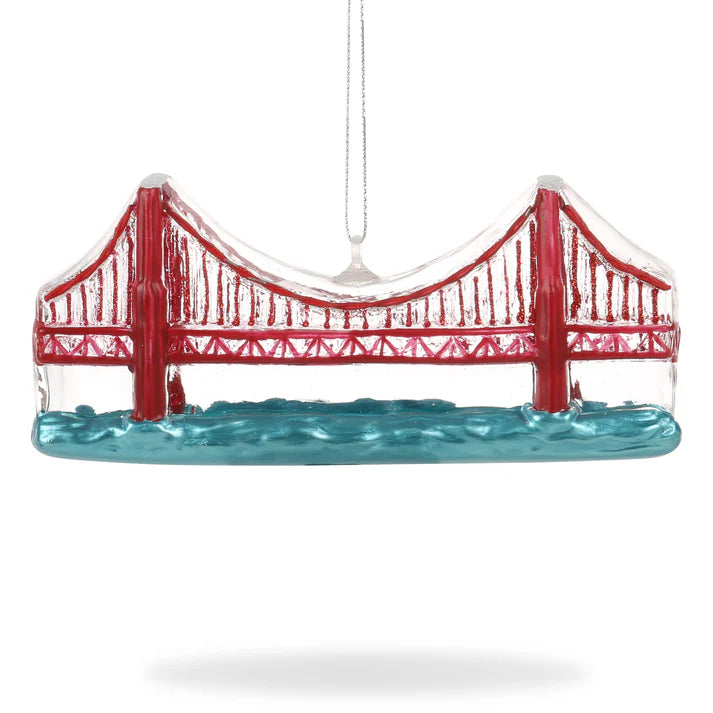 Locally inspired, the Xmas Ornaments - Local Elves hand-painted glass piece showcases a red suspension bridge elegantly spanning over blue waters, suspended by a slender wire.