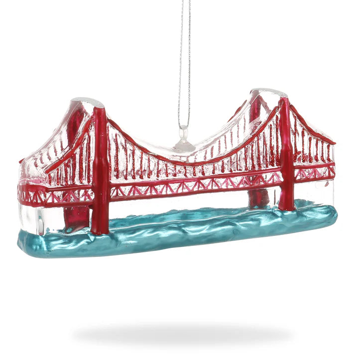 This hand-painted glass ornament from the Xmas Ornaments - Local Elves collection elegantly hangs on a string, drawing inspiration from the iconic red suspension bridge. With blue water depicted below, it beautifully encapsulates the essence of architectural beauty.