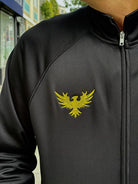 A person wearing the WC x SFP Zip-Up Jacket, featuring a yellow phoenix emblem on the chest.