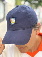 Wearing the WC x SFP Patched Hat with an embroidered crest, a person bows their head and touches the brim—subtly showing support for the US Men's National Team.