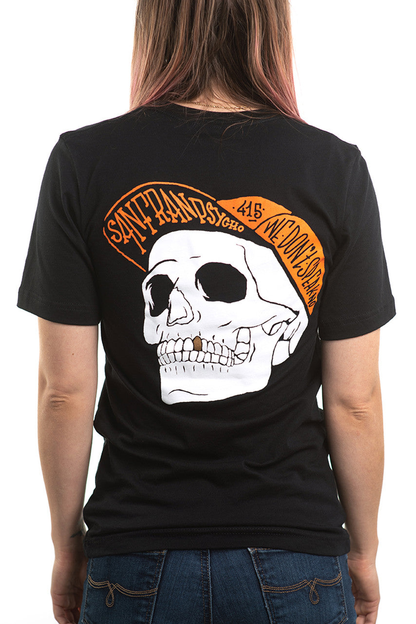 The person is wearing the Black & Orange Street Skull Tee, distinguished by its bold black design, prominently displaying a large hand-printed skull on the back with vibrant orange text encircling it. Made from soft Airlume cotton, this shirt seamlessly blends comfort with an edgy style.