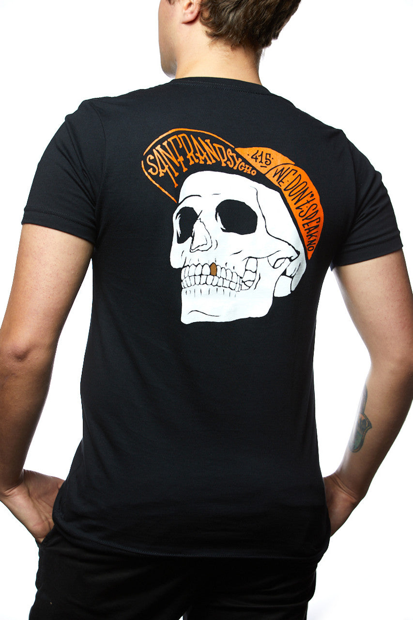 A person wearing the Black & Orange Street Skull Tee, made from soft Airlume cotton and featuring a bold hand-printed skull with an orange cap graphic on the back.