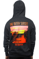 A person strolls down Noriega St, sporting an Outer Sunset Zip-Up Hoodie featuring the words "The Outer Sunset" alongside "San Franpsycho," complemented by a vibrant sunset graphic.