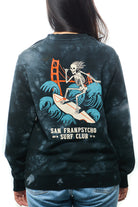 A person wearing the Surf Club Crewneck, which features a super soft fabric and displays a skeleton surfing design alongside the San Franpsycho Surf Club text.
