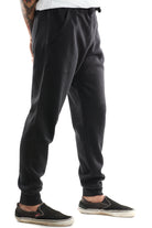 A person dressed in Black & Orange Embroidered Logo Joggers paired with comfy black slip-on shoes featuring crisp white soles.