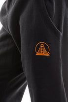 Close-up of Black & Orange Embroidered Logo Joggers, highlighting the comfortable fleece material and an orange Golden Gate Bridge logo near the pocket.