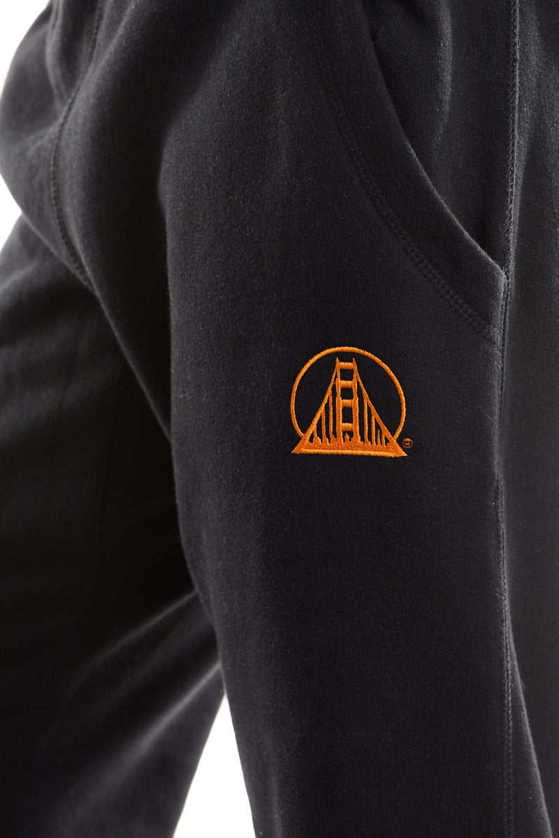 Close-up of Black & Orange Embroidered Logo Joggers, highlighting the comfortable fleece material and an orange Golden Gate Bridge logo near the pocket.