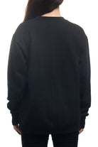 Back view of a person wearing the Black & White Logo Crewneck sweatshirt paired with black pants, facing away from the camera.