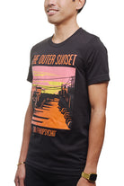 A man wears the Outer Sunset Tee, featuring vibrant sunset graphics and the phrase "The Outer Sunset, San Franpsycho," embodying the relaxed vibe of San Francisco.
