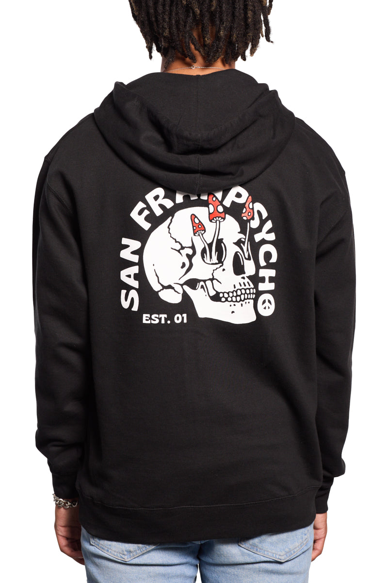 A person wearing the Shroom Skull Zip-Up Hoodie in black, showcasing a hand-printed skull and mushrooms graphic with San Fran Psycho text and Est. 01. It is crafted from 100% cotton for ultimate comfort.