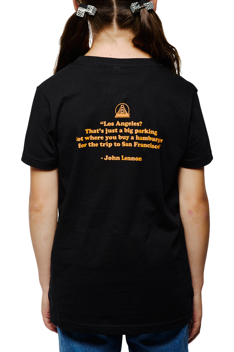 A child wearing the Youth Beat LA Tee in black & orange, featuring a John Lennon quote printed in yellow text on the back.