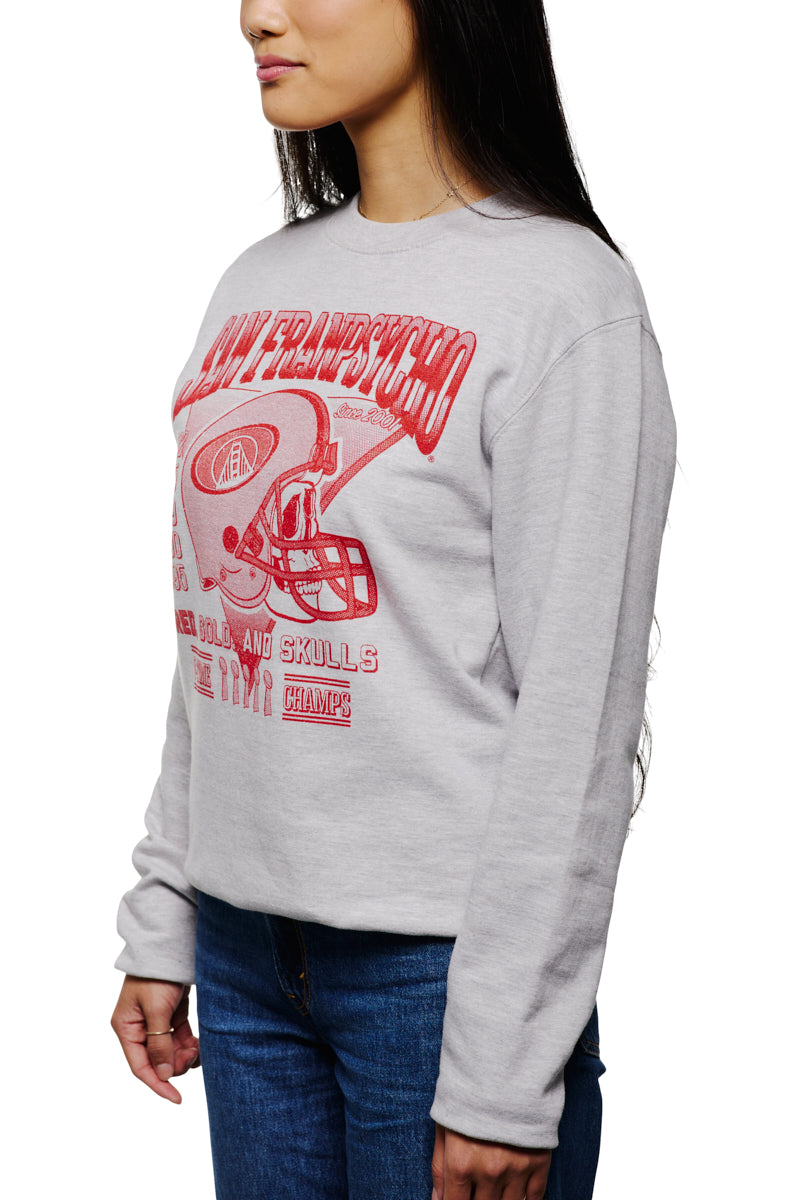 A person wearing the Candlestick Champs Crewneck, a vintage gray sweatshirt featuring a red football helmet design representing the Niners season, paired with blue jeans.