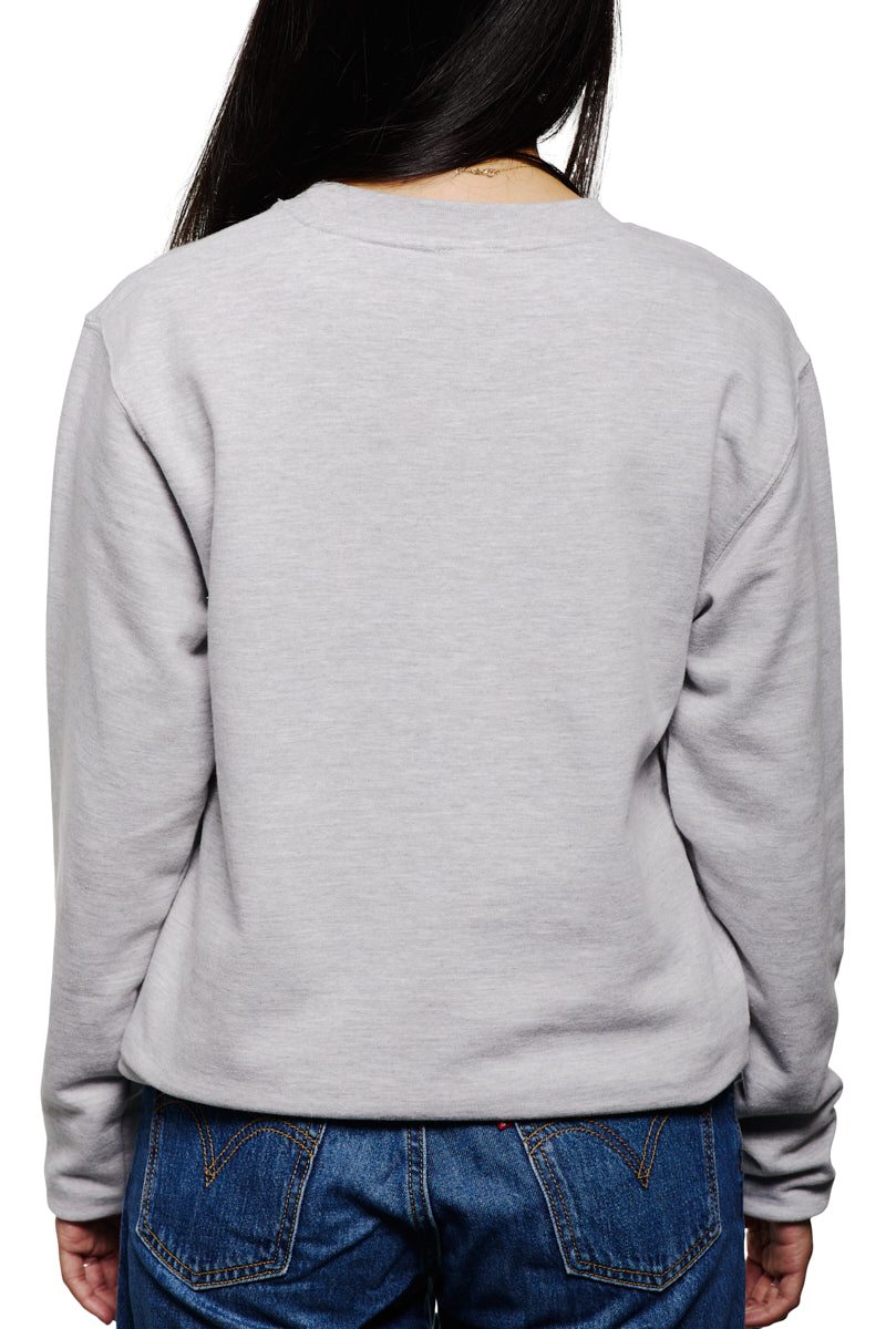 A person with long hair in a vintage sweatshirt and blue jeans faces away, exuding a timeless cool with their Candlestick Champs Crewneck.