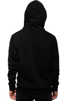 A person in a Black Muir Woods Patched Zip-Up Hoodie, hood raised and facing away against a white backdrop, evokes the spirit of "Free To Wander," offering a comfort as natural as 100% cotton.