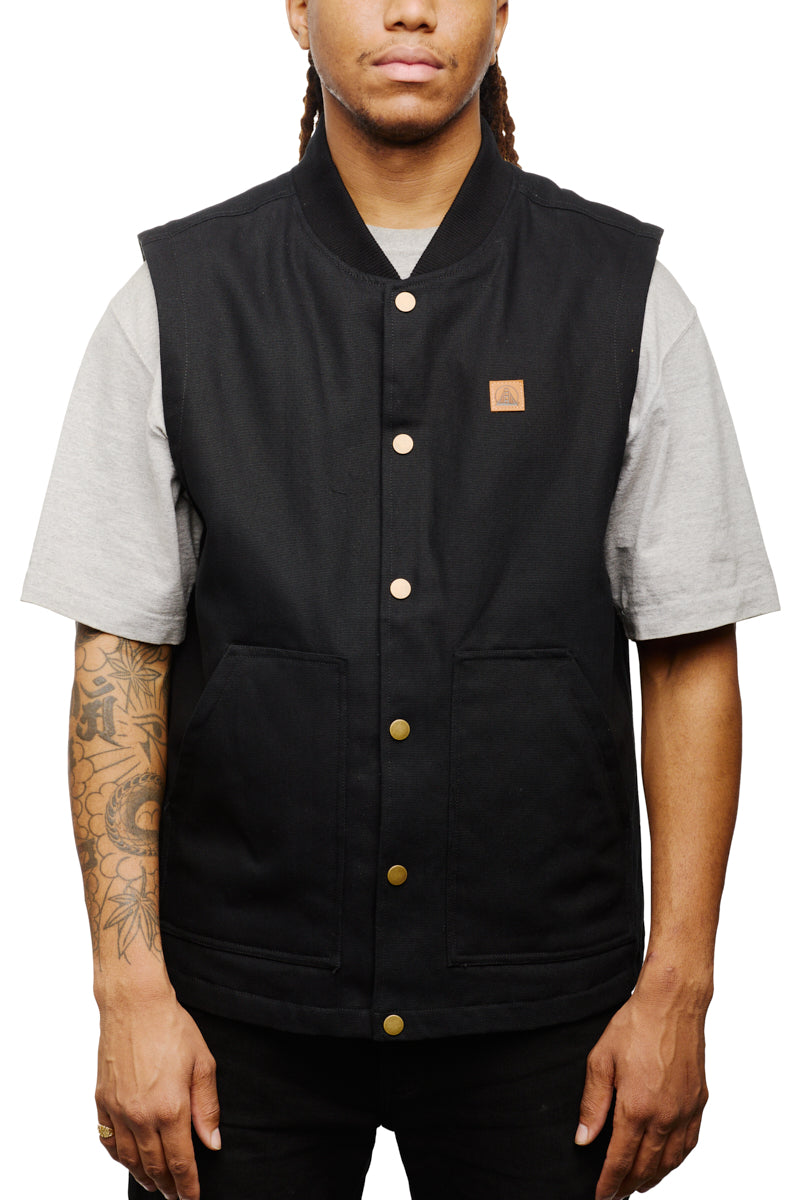 Person sporting a black Leather Patch Workwear Vest over a gray t-shirt, with tattoos visible on their right arm.