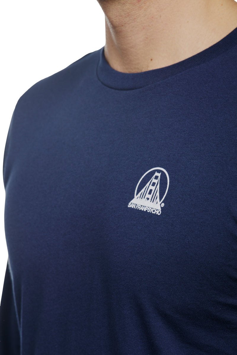 A man wears a navy long sleeve tee with a white San Francisco bridge mini logo on the chest, made from soft Airlume cotton for superior comfort and style. (Product: Navy Long Sleeve Mini Logo).