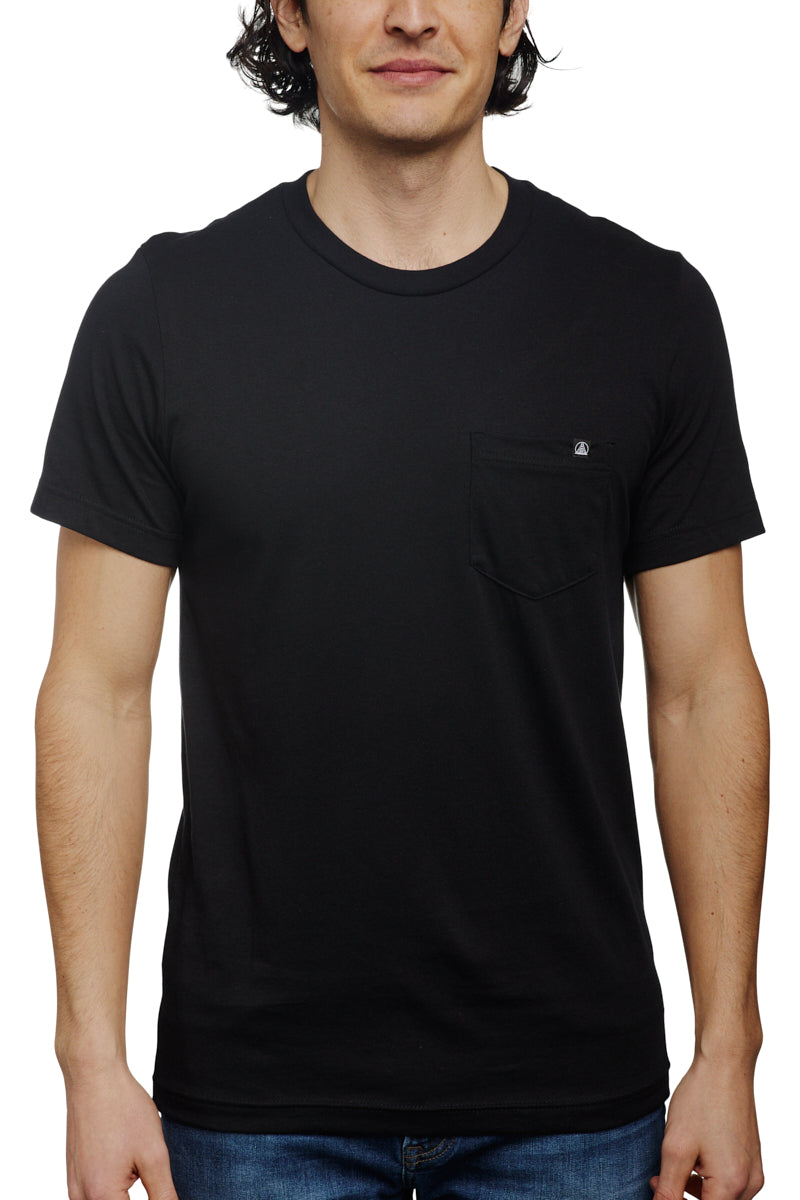A man stands against a white background wearing the Black Pocket Tee w/ SFP Clip Label, crafted from Airlume cotton, epitomizing the basics line.