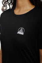 A woman wearing a Women's Mini Logo Tee from the basics line, featuring a white San Francisco bridge design in black.