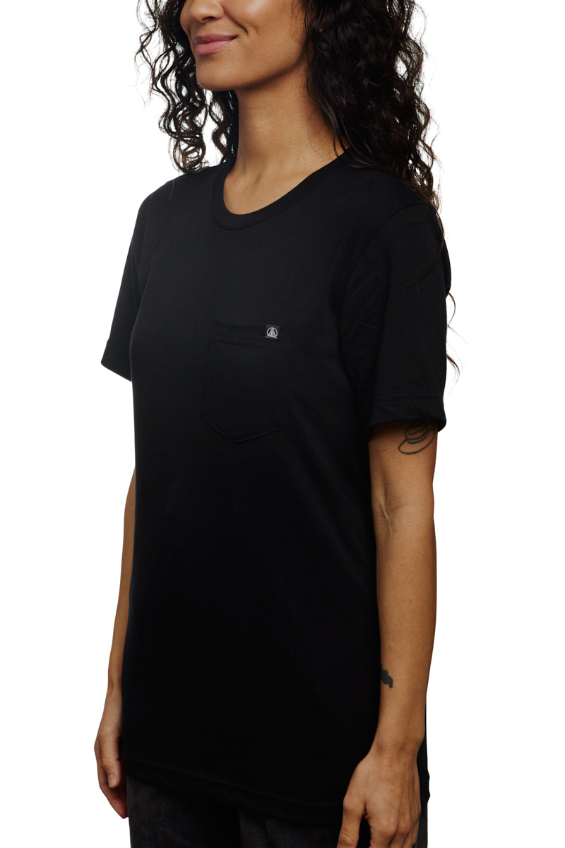 The person is wearing a sleek Black Pocket Tee w/ SFP Clip Label from the basics line, crafted from premium Airlume cotton, and stands confidently against a white background.