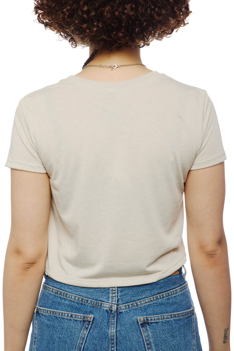 A person with curly hair is seen from behind, wearing a Trippy Psycho Crop Top in white and blue jeans from the Spring 2023 Collection, hand printed in San Francisco.