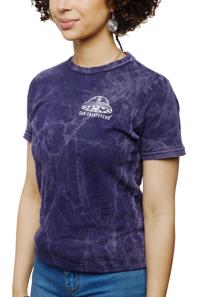 A woman is wearing the Psycho Invader Mineral Wash Tee from the Spring 2023 Collection, showcasing the San Franpsycho logo. She pairs it with earrings and blue jeans, effortlessly merging style and comfort.