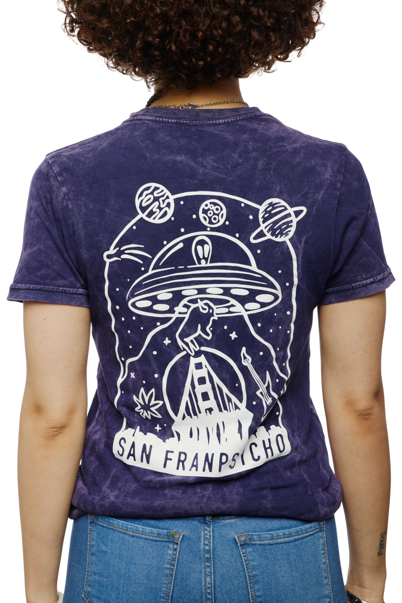 A person is viewed from behind, sporting a purple Psycho Invader Mineral Wash Tee featuring a captivating UFO and planets design, labeled San Francisco. This standout piece from the Spring 2023 Collection draws attention with its bold artwork.