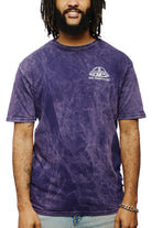 Man wearing a purple Psycho Invader Mineral Wash Tee featuring the San Franspsycho logo, smiling with hands by his sides, as part of the vibrant Spring 2023 Collection.