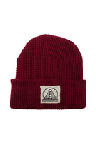 The Burgundy Waffle Beanie w/ Natural/Black SFP Logo features a soft acrylic build, a folded brim, and a white patch with a bridge graphic and bold text.