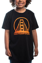 A child smiles brightly, wearing the Youth Black & Orange Logo Tee that showcases an orange bridge logo and the iconic San Franpsycho text, capturing the vibrant spirit of San Francisco.